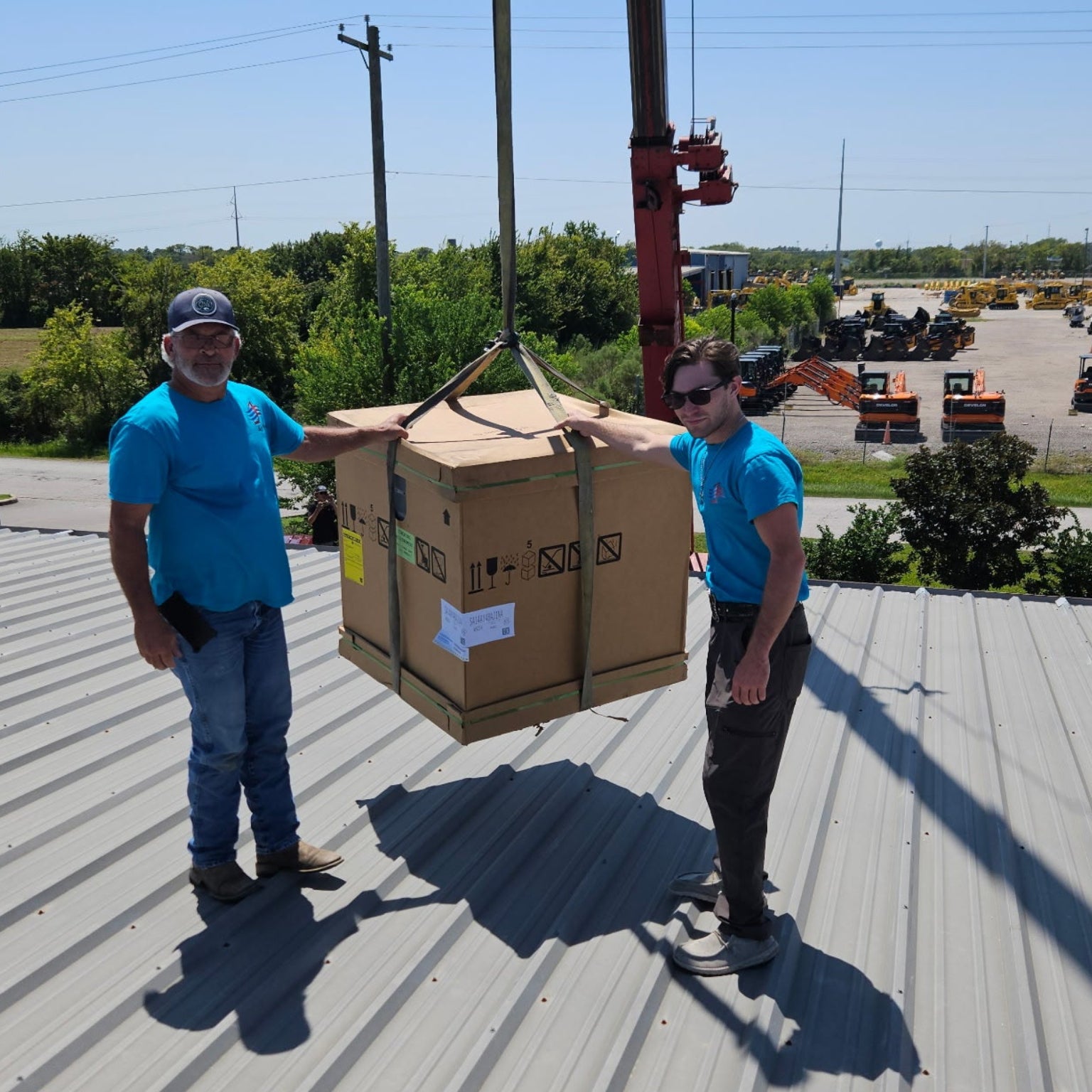 Elan and Evan Melvin are on a roof with a large box being lifted by a crane.